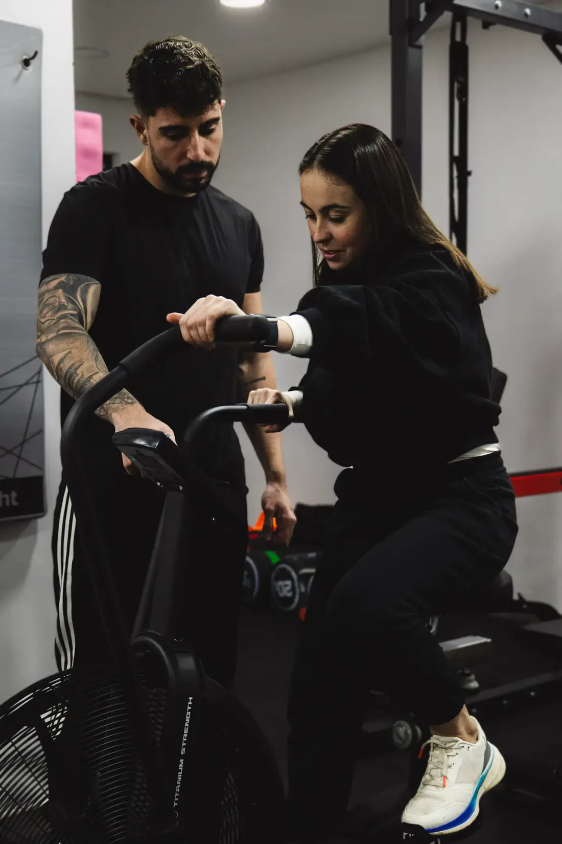 Entrenador supervisando a una clienta en bicicleta de aire